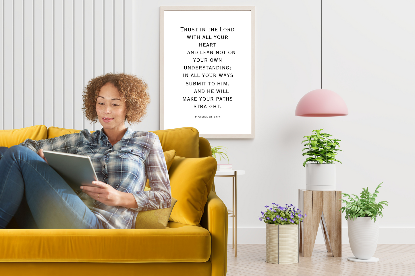 Proverbs 3:5 motivational wall art printable styled in a modern living room, with a woman sitting on a yellow couch reading a tablet.
