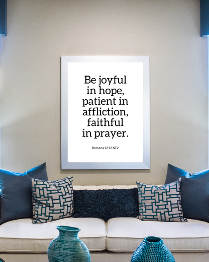 Motivational Christian wall decor of Romans 12:12 displayed in a living room setting with neutral and blue tones. 