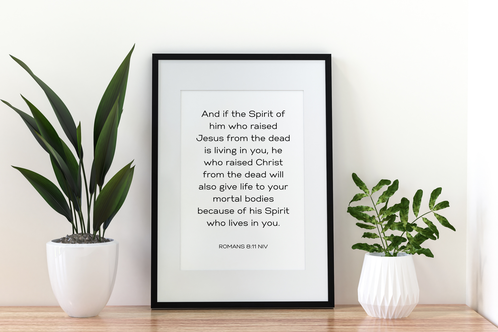 Inspirational Christian scripture typography print of Romans 8:11 in a hallway with clean contemporary styling.