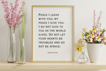 Printable typography wall art featuring John 14:27 framed in a simplistic hallway setting with white walls and minimalist floral decor.

